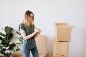 woman moving, moving boxes in living room, first apartment checklist